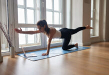 Die Bedeutung des Online Training Yoga lessons online. Positive yoga girl doing morning practice in front of laptop at home.